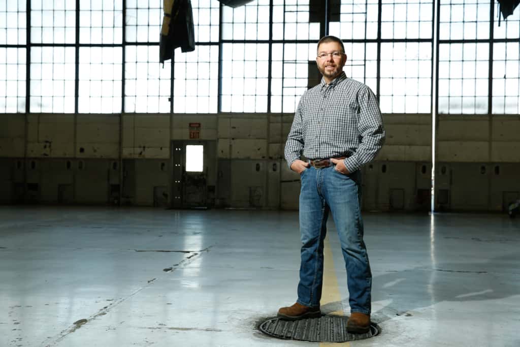 Mike Bevis stands in an open warehouse, hands in his pocket.