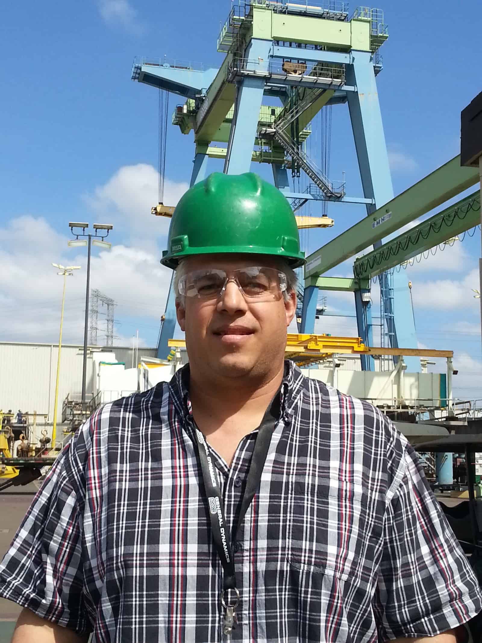 Tony Silva stands in front of a container crane wearing a hard hat