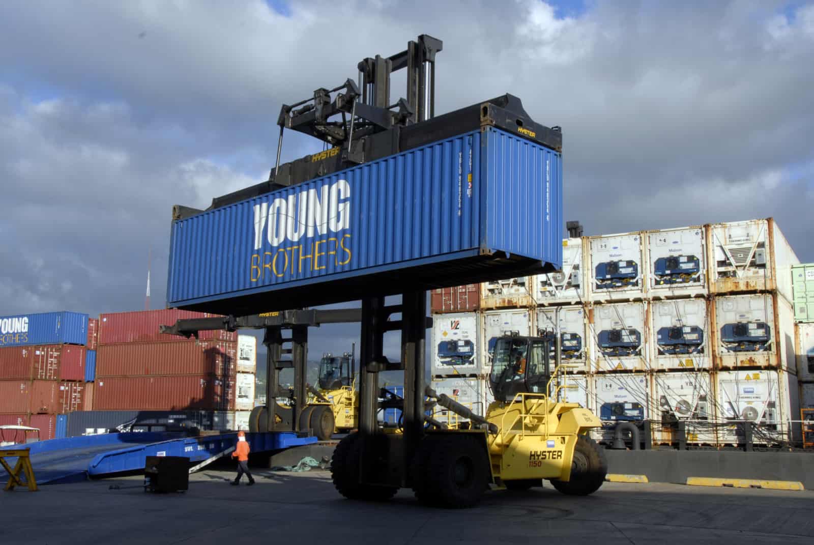 A container forklift holds a Young Brothers container high in a shipping yard.