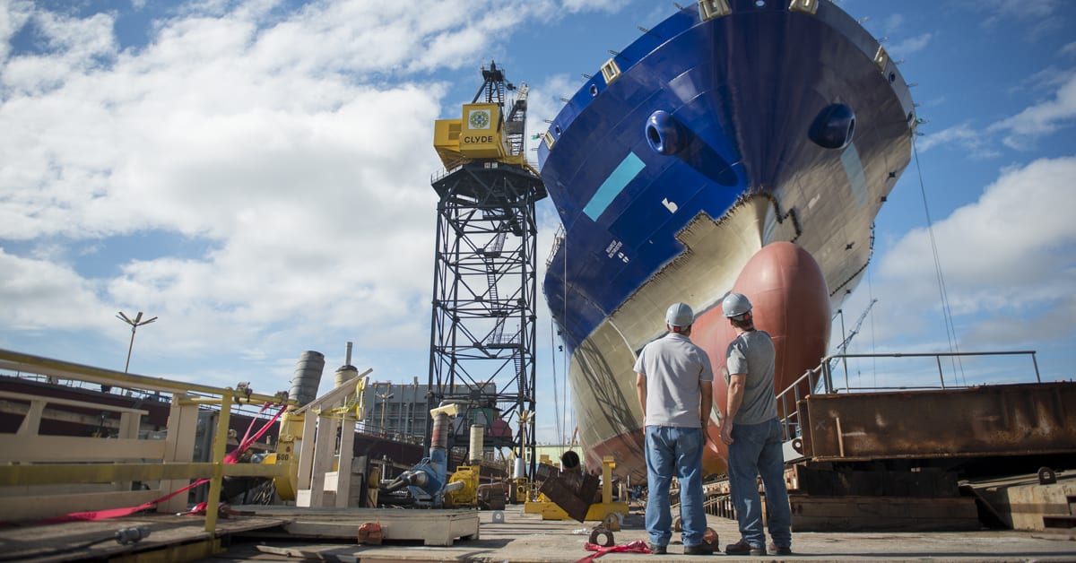 Workers stand under a TOTE ship being serviced at NASSCO in San Diego.