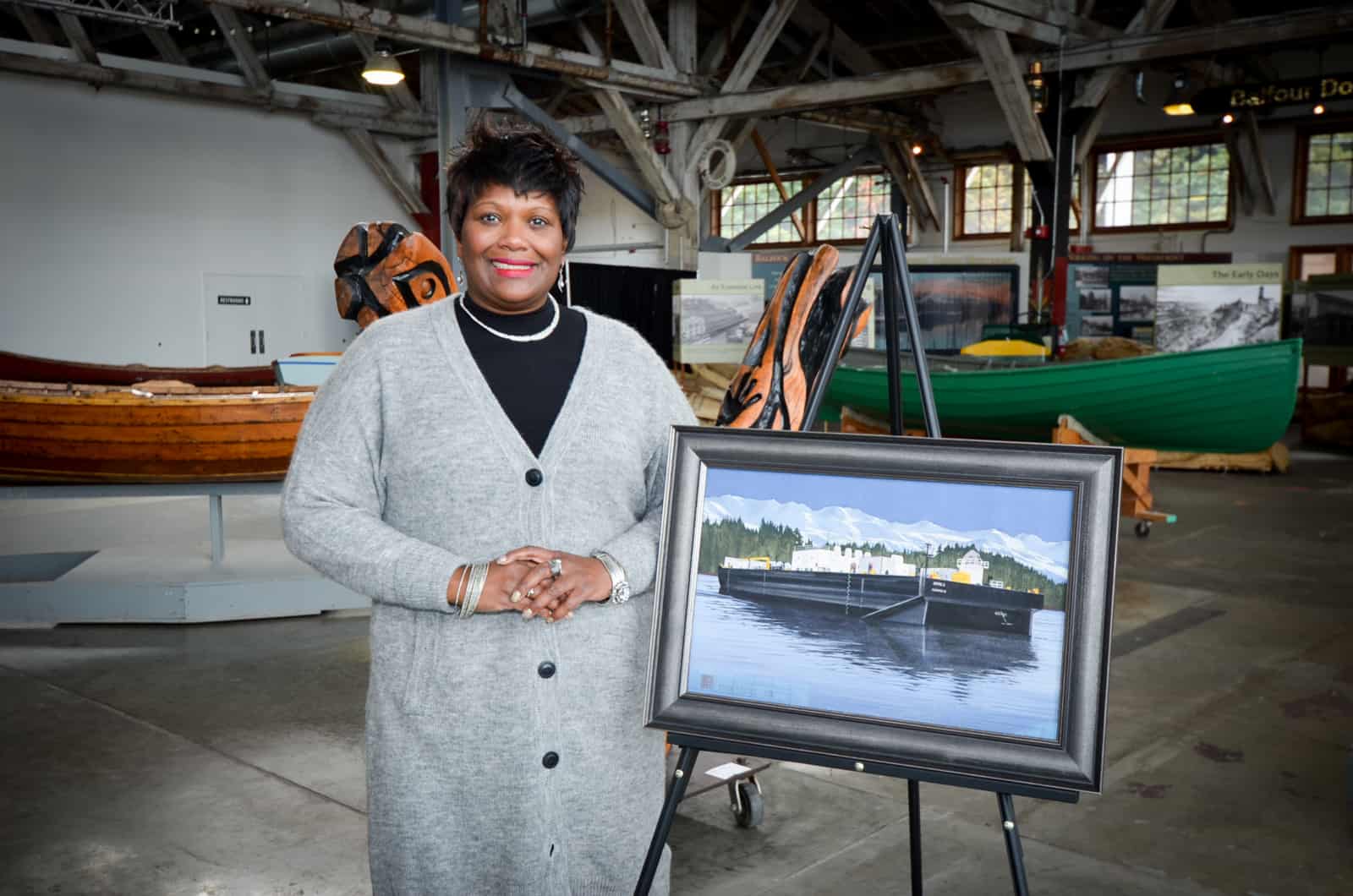 Benita stands next to a painting of the Antril S. in the Foss Waterway Seaport Museum in Tacoma