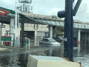 A car floats at a gas station ravaged by a storm.