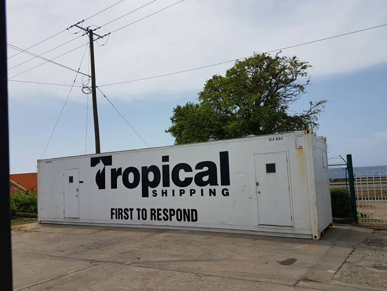 A disaster response trailer sits in a lot with the words, "Tropical Shipping First to Respond" painted on the side.
