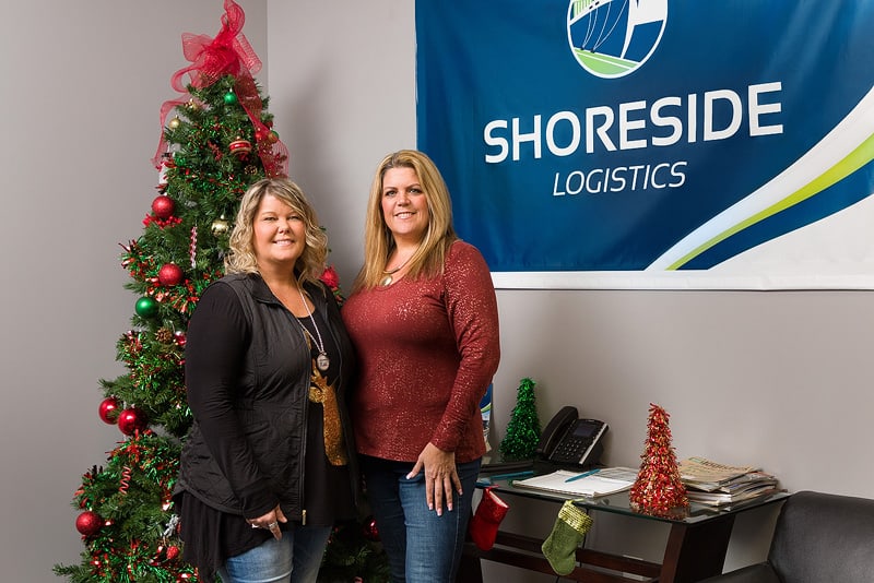 Stephanie and Stacey pose in front of a Christmas tree in Shoreside Logistic's offices.