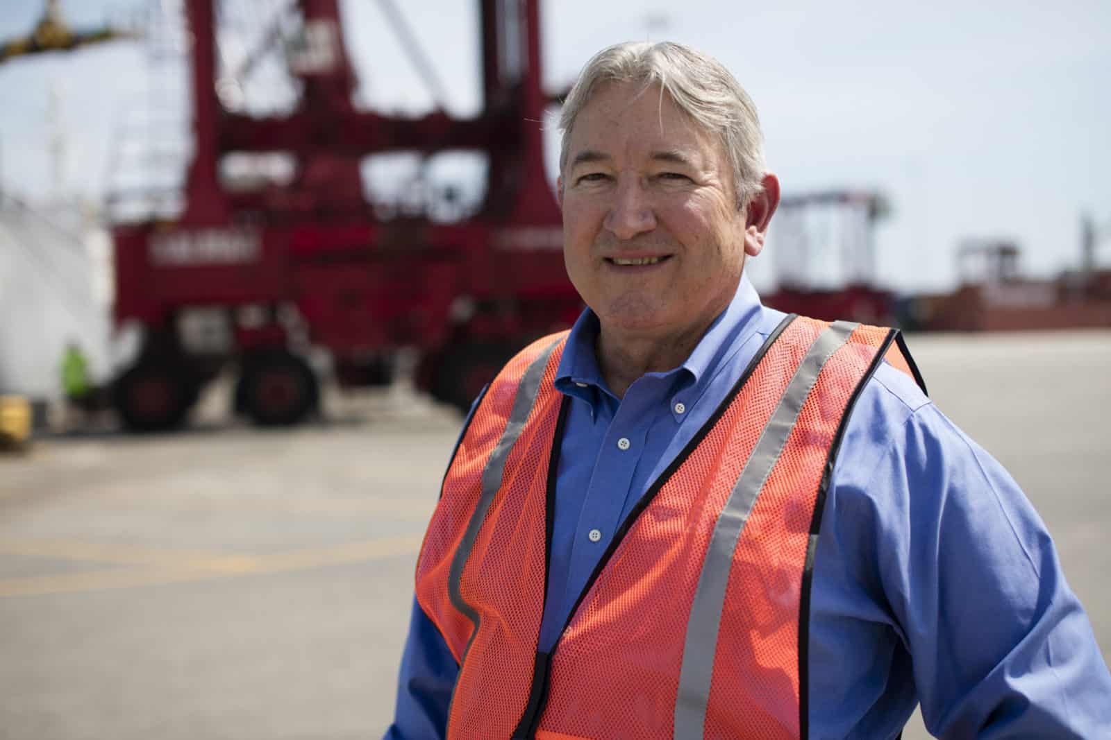 Culpepper poses, in an orange reflective vest, standing in a shipyard.