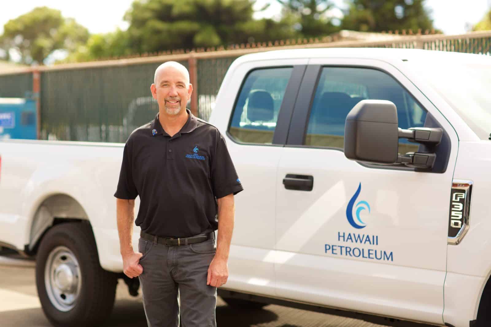 Wetter stands and smiles in front of a Hawaii Petroleum pick up truck.