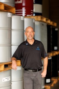 Wetter leans on a tower of barrels wearing a Hawaii Petroleum polo shirt.