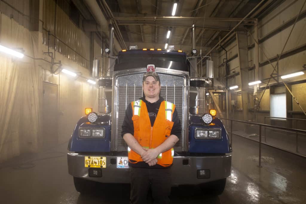 Caskey poses in front of a Carlile truck indoors.