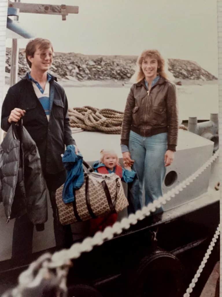 Young Katrina wears a life vest between her parents on a tug boat.