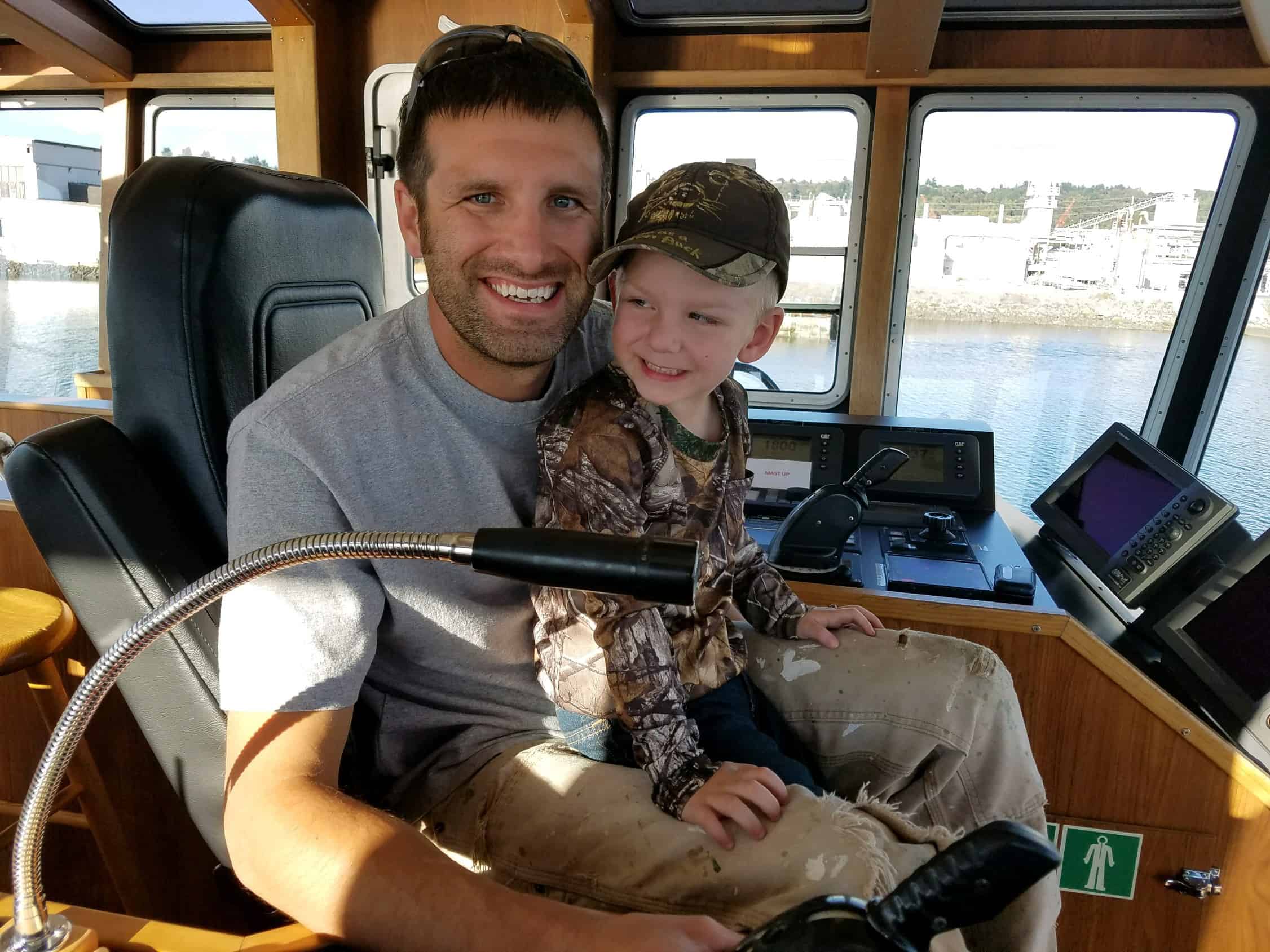Andy holds his son in his lap at the helm of a Foss tug.