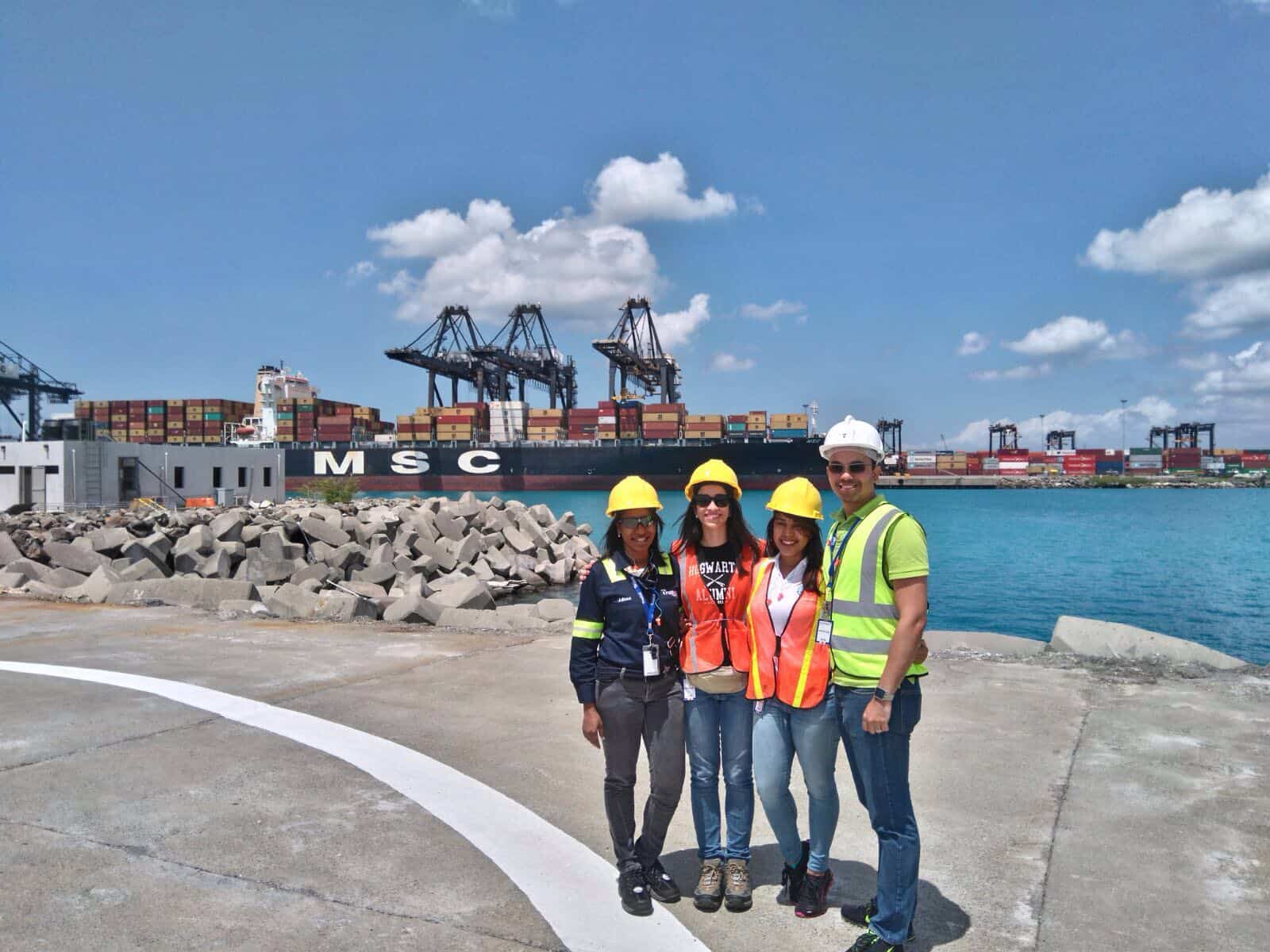 Julissa Moreta poses in a Tropical shipyard with her family. All wear reflective vests and hard hats.