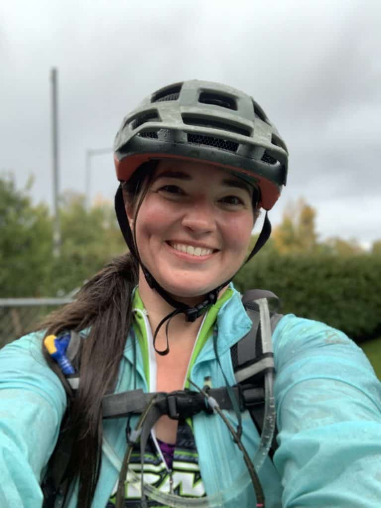 Kelly smiles for a selfie in bike helmet and rain gear.
