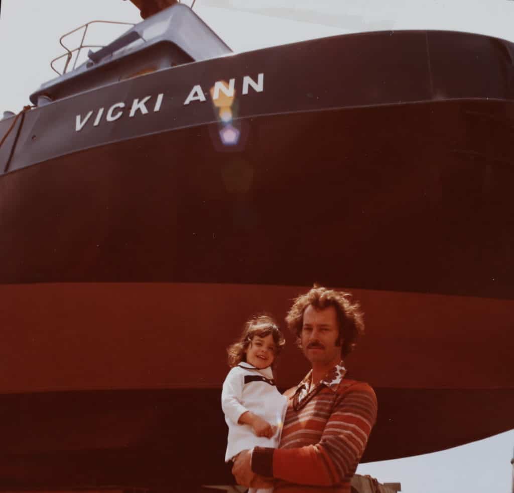 Vicki is held by her father under the Vicki Ann.