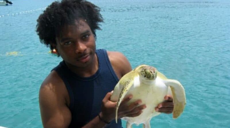 Younger Kemit-Amon Lewis holds a young sea turtle.