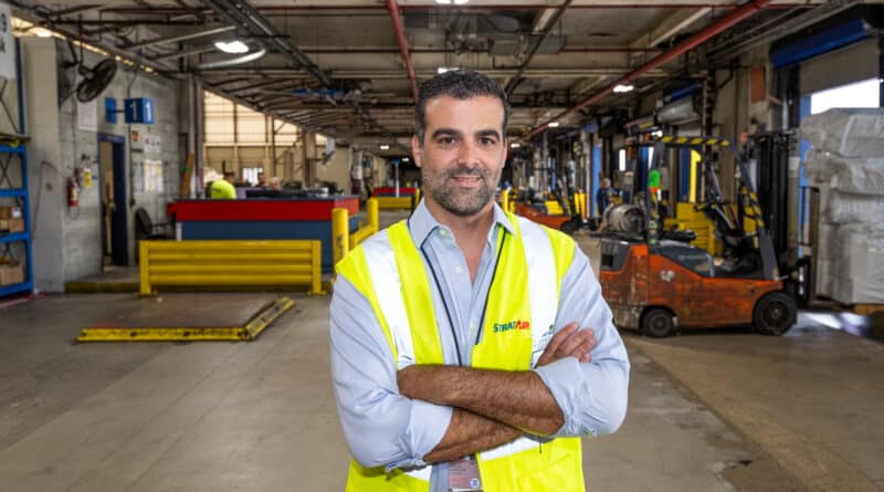 Standing in a warehouse, Gonzalez crosses his arms in a yellow reflective vest.